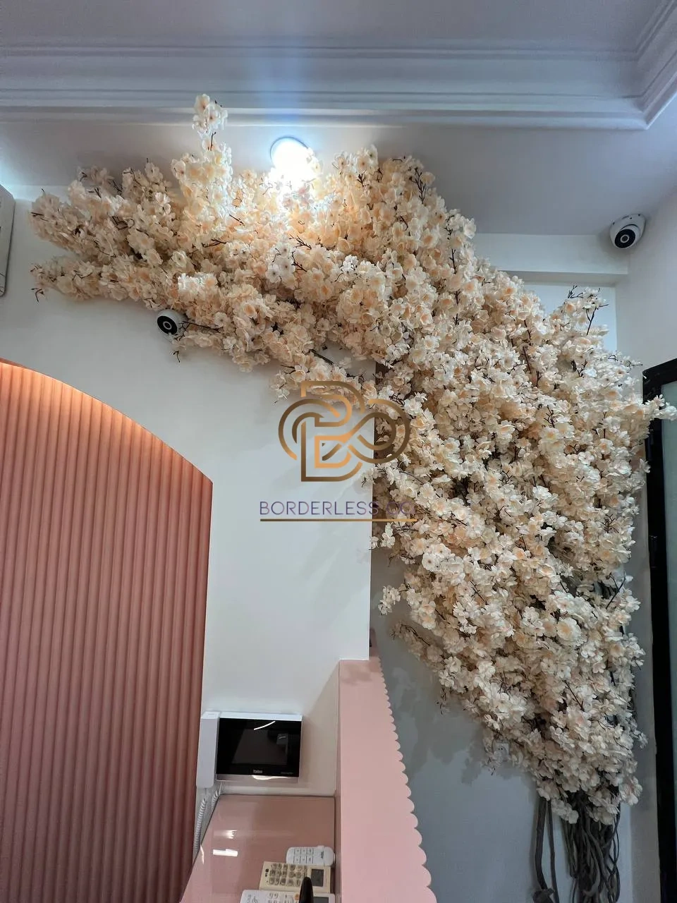 عکس واقعی ورودی با دیوار شکوفهٔ مصنوعی و قوس صورتی